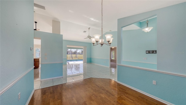 unfurnished room with ceiling fan with notable chandelier, light wood-type flooring, and vaulted ceiling