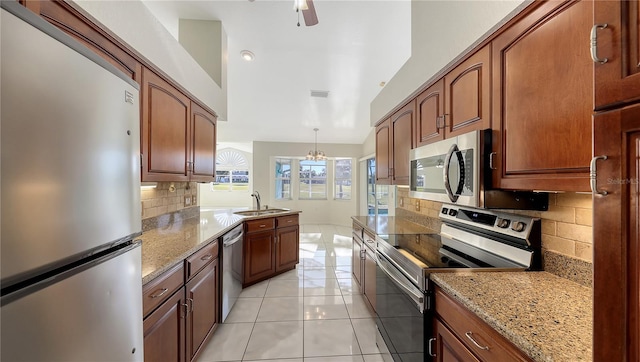 kitchen with hanging light fixtures, sink, light tile patterned floors, appliances with stainless steel finishes, and tasteful backsplash