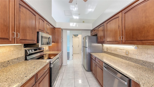 kitchen featuring decorative backsplash, appliances with stainless steel finishes, light stone counters, ceiling fan, and light tile patterned floors