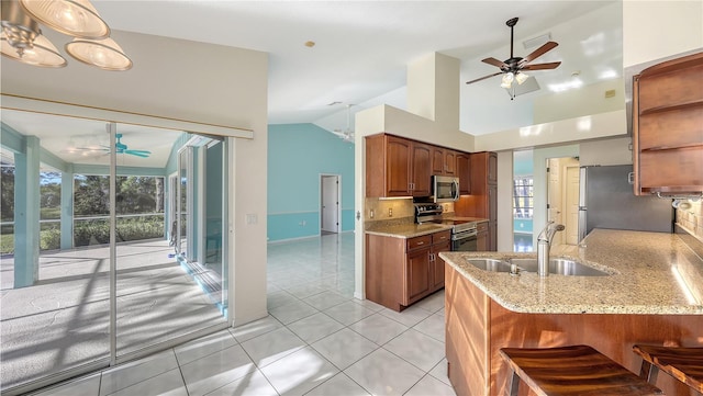 kitchen featuring backsplash, sink, light stone countertops, appliances with stainless steel finishes, and kitchen peninsula