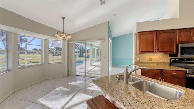 kitchen with decorative light fixtures, stainless steel appliances, a wealth of natural light, and vaulted ceiling