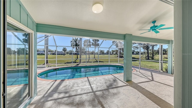 view of swimming pool featuring a patio area, ceiling fan, and glass enclosure