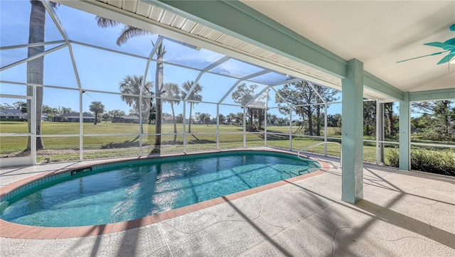 view of pool with glass enclosure, ceiling fan, and a patio area