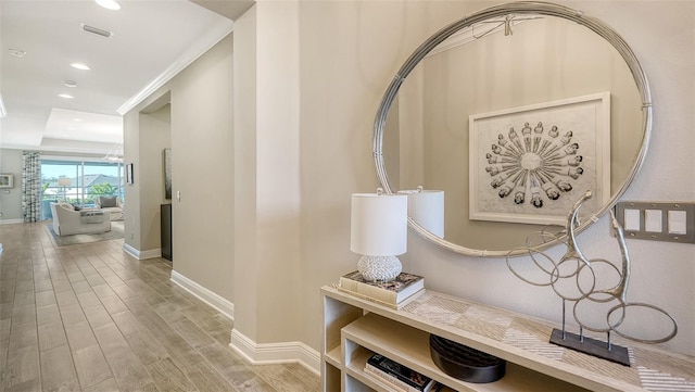 mudroom with a raised ceiling and crown molding