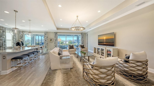 living room featuring a tray ceiling, hardwood / wood-style floors, and a notable chandelier