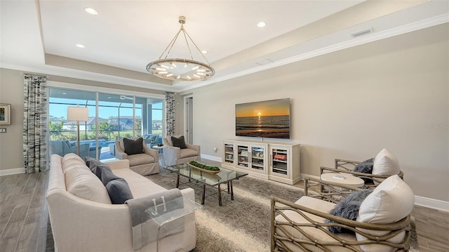 living room with a raised ceiling, hardwood / wood-style floors, and an inviting chandelier