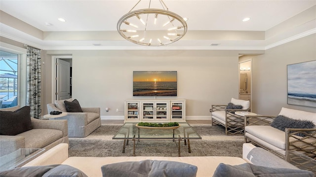 living room with a raised ceiling, an inviting chandelier, and crown molding