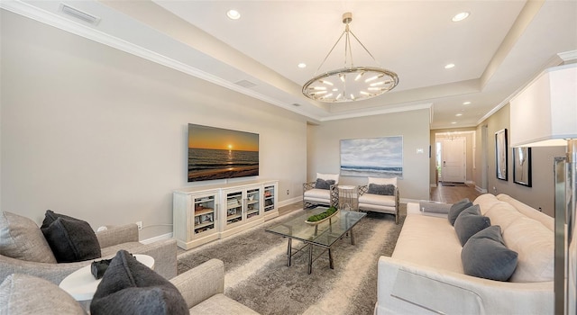 living room with a chandelier, a tray ceiling, and crown molding