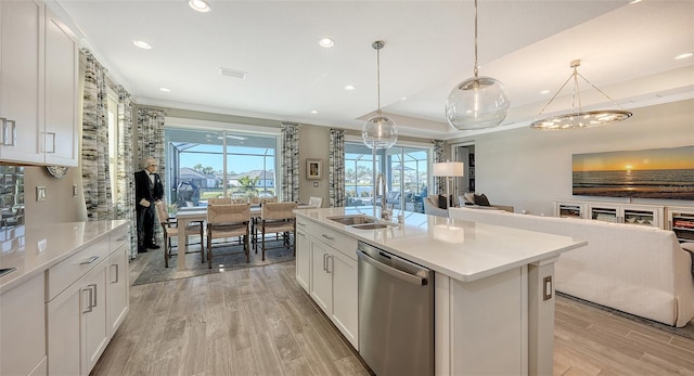 kitchen with white cabinets, decorative light fixtures, a center island with sink, and stainless steel dishwasher