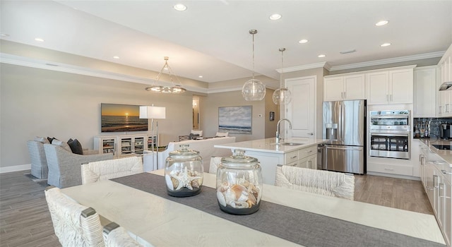 kitchen featuring stainless steel appliances, sink, a center island with sink, light hardwood / wood-style flooring, and white cabinetry