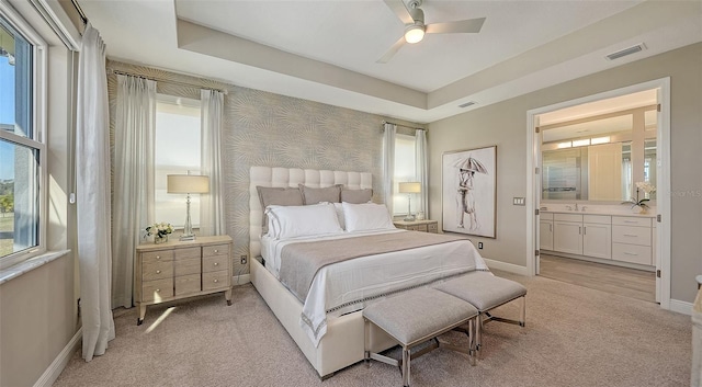 bedroom featuring ceiling fan, a raised ceiling, light colored carpet, and multiple windows