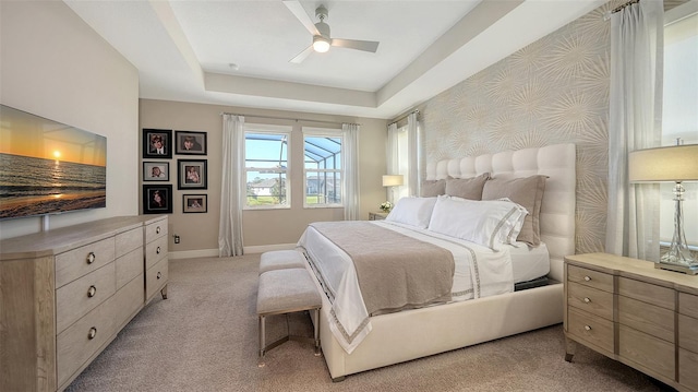 bedroom featuring light carpet, a raised ceiling, and ceiling fan