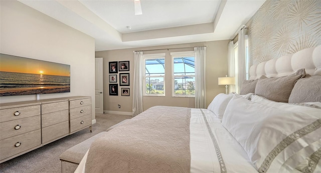 bedroom featuring ceiling fan, a raised ceiling, and light carpet