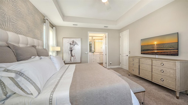 carpeted bedroom with connected bathroom, a tray ceiling, and ceiling fan