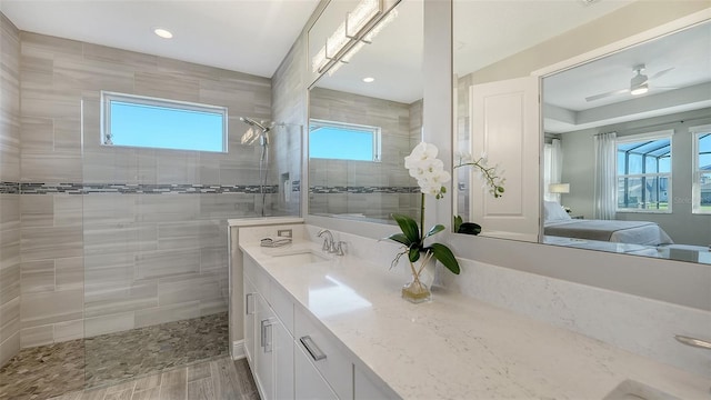 bathroom featuring ceiling fan, vanity, and tiled shower