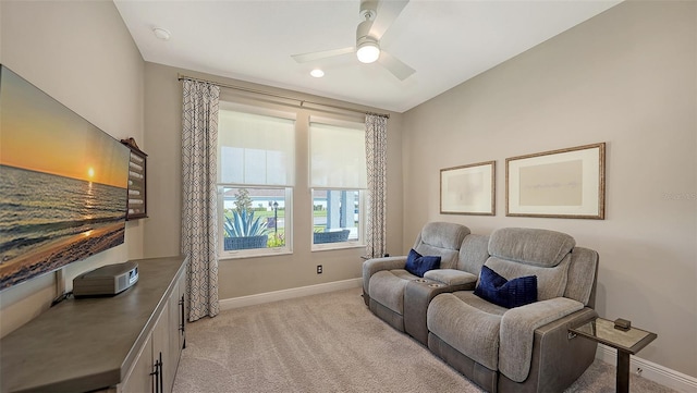 living area with light colored carpet and ceiling fan