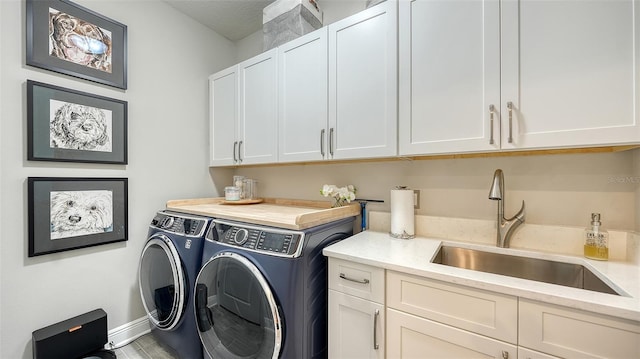 clothes washing area featuring washing machine and dryer, sink, and cabinets