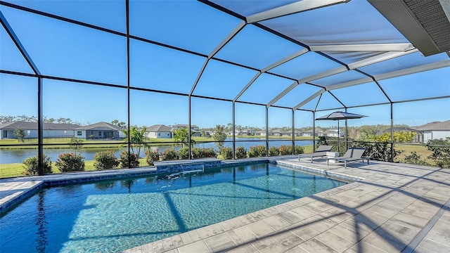 view of pool featuring glass enclosure, a patio area, and a water view