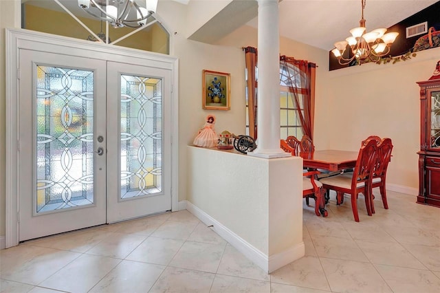 tiled foyer entrance featuring a chandelier, french doors, and decorative columns