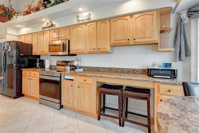 kitchen featuring appliances with stainless steel finishes, light brown cabinets, light stone counters, and light tile patterned flooring