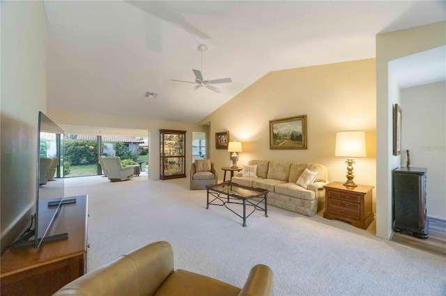 carpeted living room with ceiling fan and vaulted ceiling