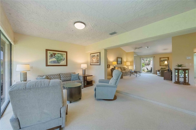 carpeted living room with a textured ceiling and ceiling fan