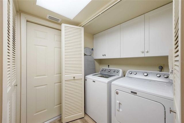 clothes washing area featuring washer and clothes dryer, light hardwood / wood-style floors, and cabinets