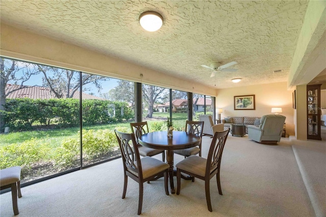 carpeted dining space with a textured ceiling and ceiling fan