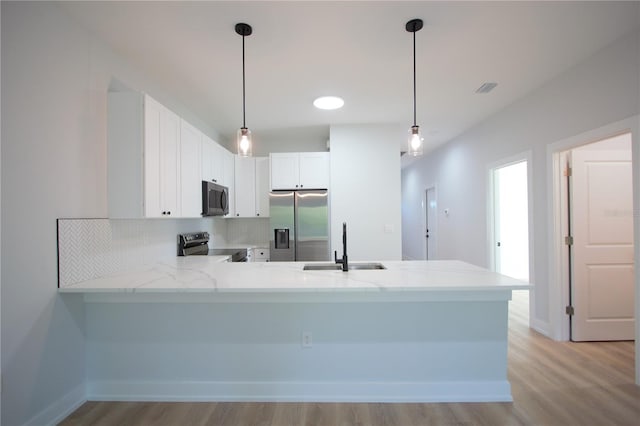 6779 David Blvd, Port Charlotte, FL 33981 - kitchen with appliances with stainless steel finishes, a peninsula, light wood-type flooring, and hanging light fixtures