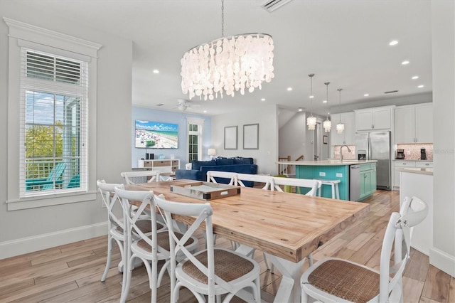 dining space with light hardwood / wood-style flooring, a notable chandelier, and sink