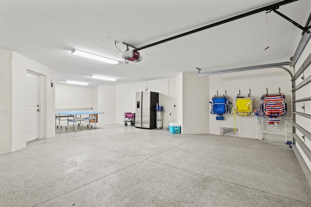 garage featuring stainless steel refrigerator with ice dispenser and a garage door opener