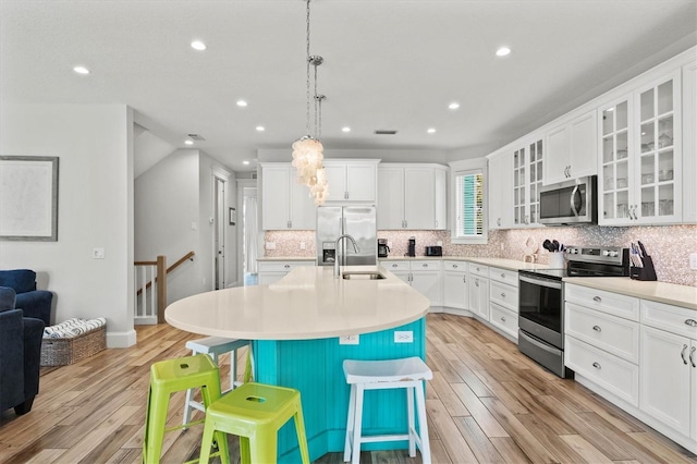 kitchen featuring appliances with stainless steel finishes, light wood-type flooring, a breakfast bar, sink, and a center island with sink