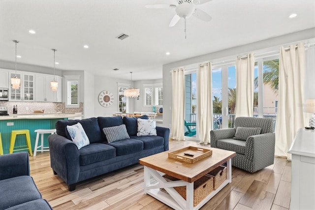 living room with ceiling fan with notable chandelier and a wealth of natural light