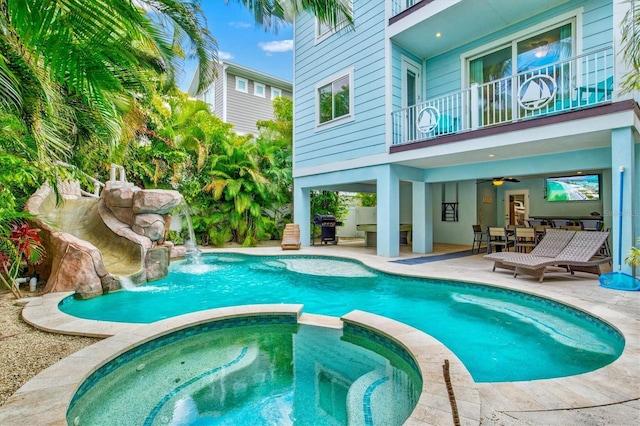 view of pool with an in ground hot tub, area for grilling, pool water feature, ceiling fan, and a patio