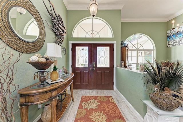 foyer entrance featuring light wood-type flooring, crown molding, and french doors