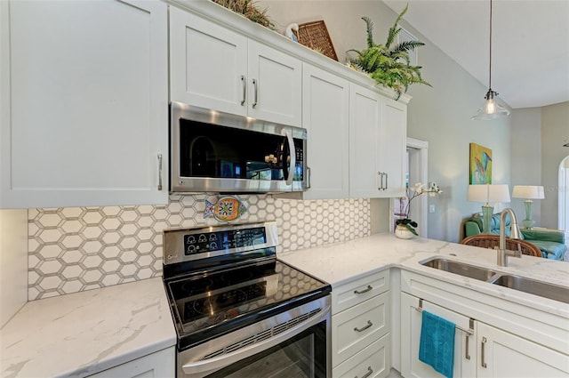 kitchen featuring hanging light fixtures, stainless steel appliances, tasteful backsplash, lofted ceiling, and white cabinets