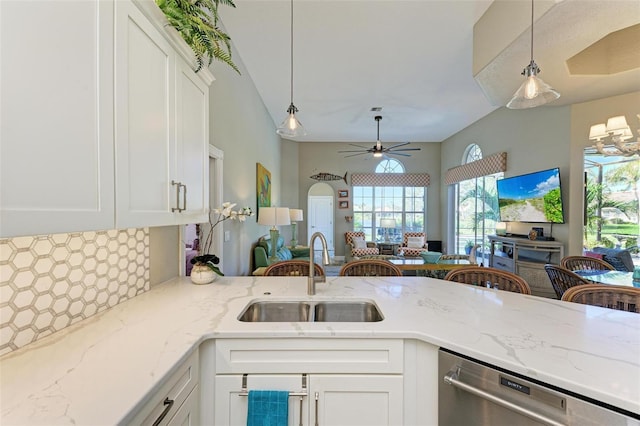 kitchen featuring light stone countertops, stainless steel dishwasher, ceiling fan, sink, and white cabinetry