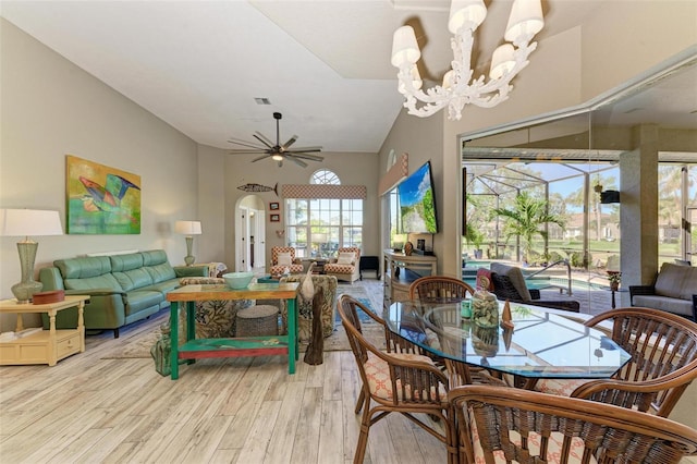 dining room with lofted ceiling, a wealth of natural light, light hardwood / wood-style floors, and ceiling fan with notable chandelier