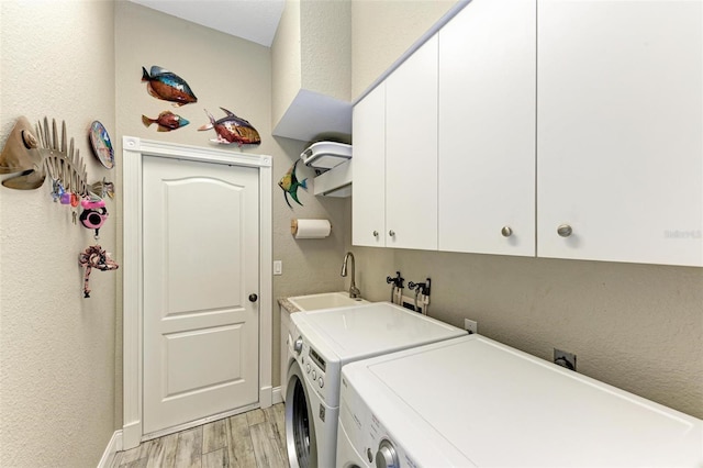 washroom with cabinets, light wood-type flooring, washer and dryer, and sink