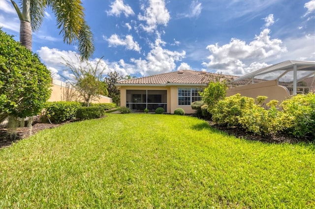 rear view of property featuring a lanai and a yard