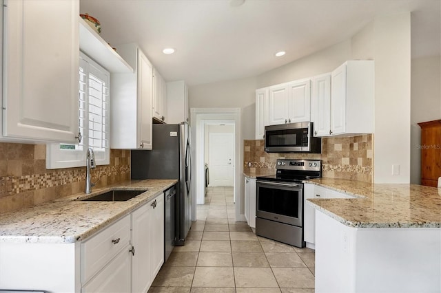 kitchen with white cabinets, appliances with stainless steel finishes, light stone counters, and sink