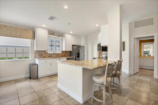 kitchen featuring white cabinets, sink, light stone countertops, appliances with stainless steel finishes, and tasteful backsplash