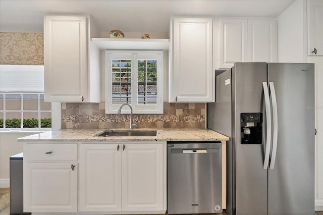 kitchen with white cabinets, sink, light stone countertops, and stainless steel appliances