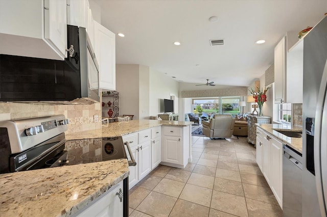 kitchen featuring kitchen peninsula, light stone countertops, stainless steel appliances, ceiling fan, and white cabinetry