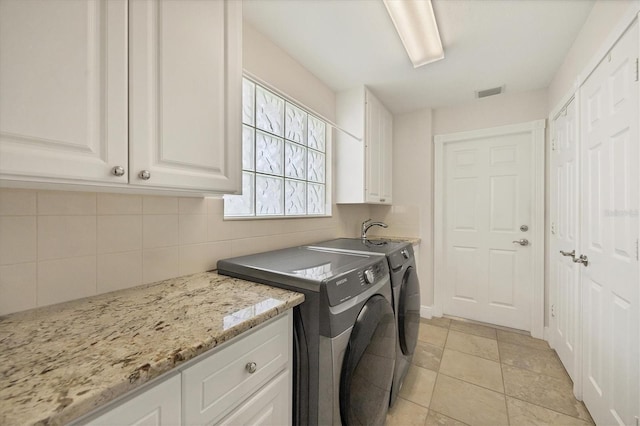 laundry room with cabinets, light tile patterned floors, and washing machine and clothes dryer