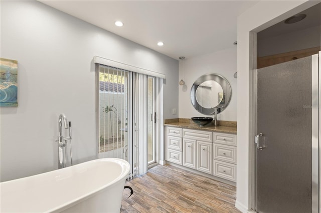 bathroom with hardwood / wood-style floors, vanity, and plus walk in shower