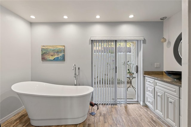 bathroom with hardwood / wood-style flooring, vanity, and a tub