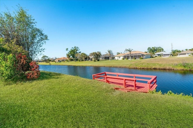 dock area with a lawn and a water view