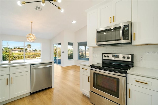 kitchen featuring a wealth of natural light, sink, stainless steel appliances, and vaulted ceiling