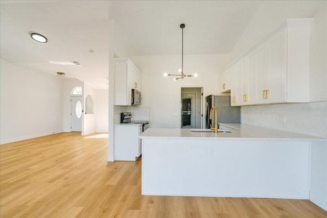 kitchen with sink, stainless steel appliances, kitchen peninsula, light hardwood / wood-style floors, and white cabinets